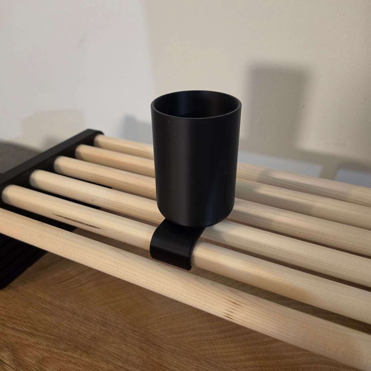 3D print lonček za pisala za modularno namizno polico v črni barvi, nameščen na leseni letveni polici za urejeno delovno mizo.